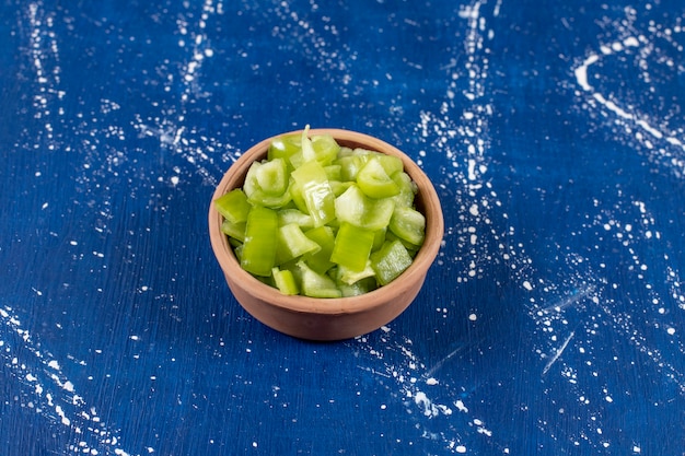 Foto gratuita ciotola di peperoni verdi affettati sulla superficie di marmo.