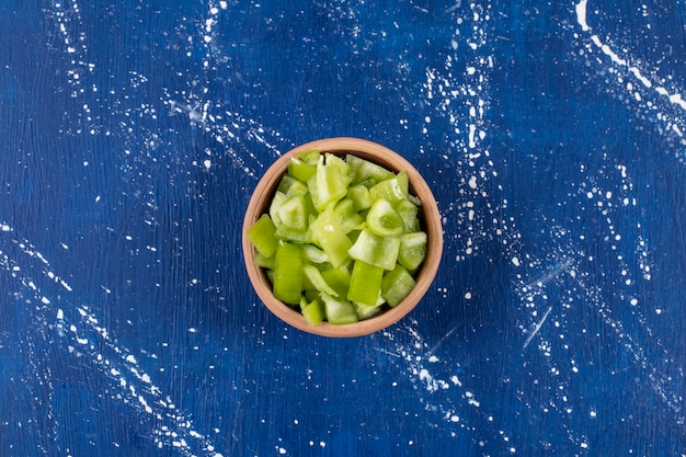 Free photo bowl of sliced green bell peppers on marble surface