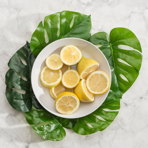 Bowl of sliced lemons with monstera leaves