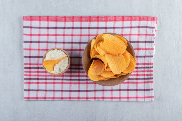 Bowl of spicy potato chips and special sauce on stone.