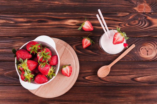 Bowl of strawberries and milkshake on table