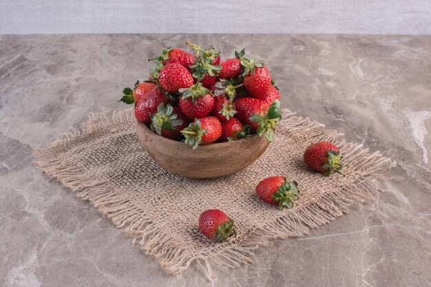 Bowl of strawberries on a piece of fabric on marble surface