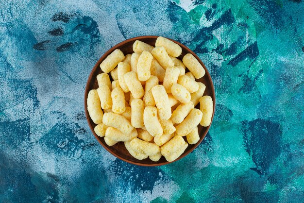 A bowl of sweet corn sticks , on the blue table.