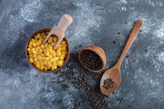 Bowl of sweet corns and grain peppers on marble.