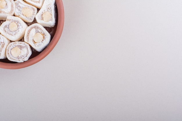 白い背景の上のナッツと甘いロクムデザートのボウル。高品質の写真