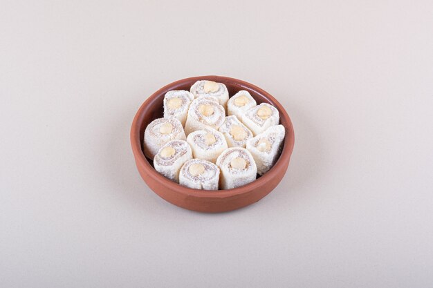 Чаша сладкого десерта лукум с орехами на белом фоне. Фото высокого качества