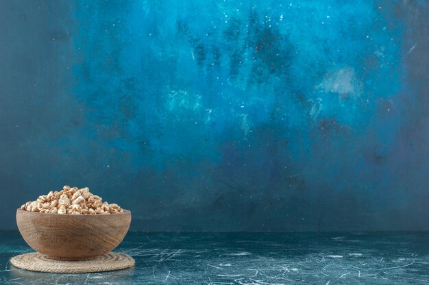 A bowl of sweet muesli on a trivet, on the blue background. High quality photo