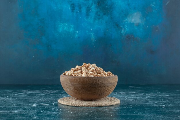 A bowl of sweet muesli on a trivet, on the blue background. High quality photo