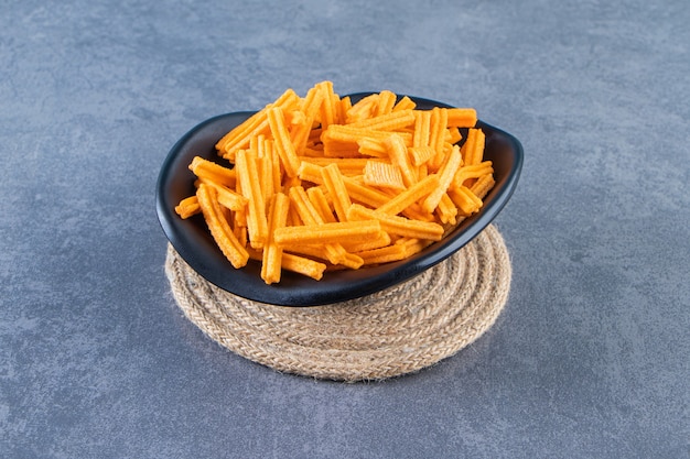 A bowl of sweet potato fries on trivet , on the marble background.