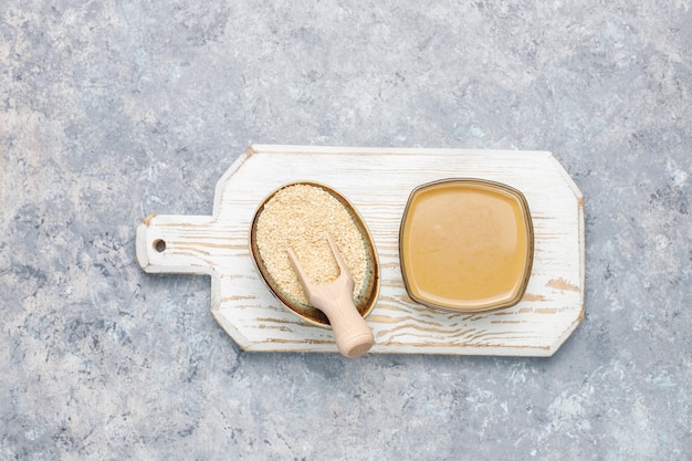 Free photo bowl of tahini with sesame seeds on concrete surface