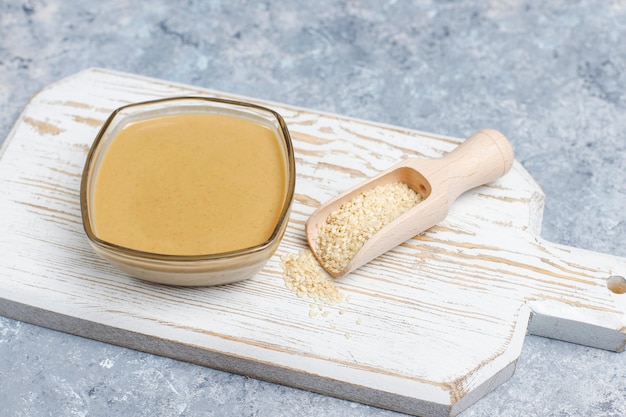 Free photo bowl of tahini with sesame seeds on concrete surface