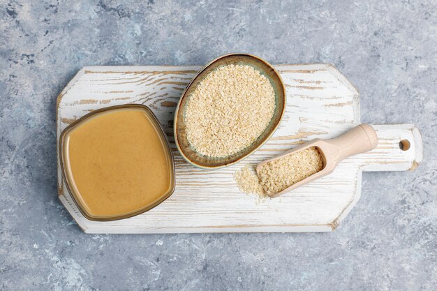 Bowl of tahini with sesame seeds on concrete surface