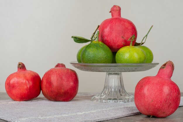 Bowl of tangerine and pomegranates on gray tablecloth.