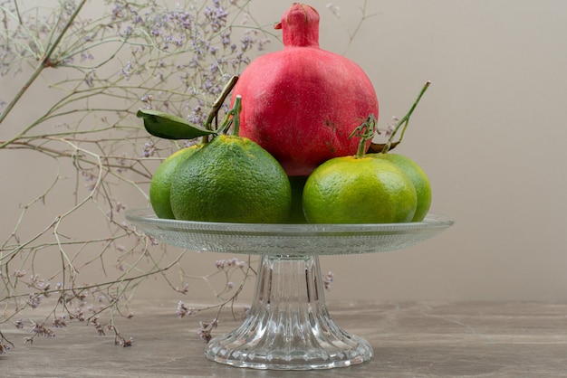 Bowl of tangerine and pomegranates on marble.