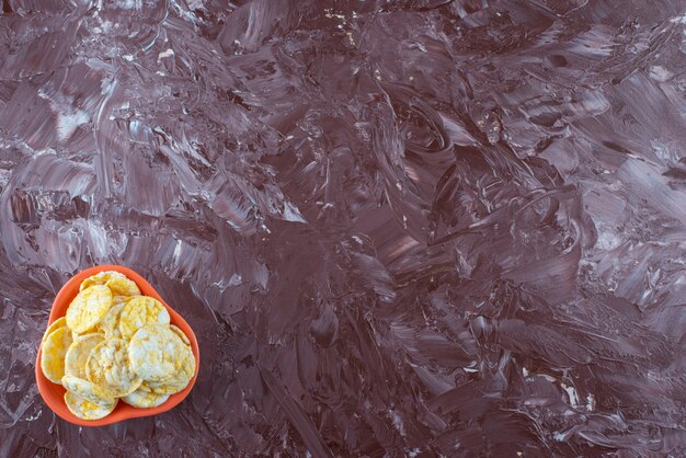 A bowl of tasty cheese chips , on the marble table. 