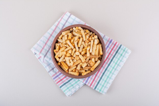 Bowl of tasty crispy crackers with tablecloth on marble background. High quality photo