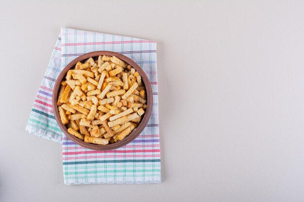 Bowl of tasty crispy crackers with tablecloth on marble background. High quality photo