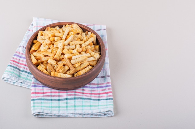 Bowl of tasty crispy crackers with tablecloth on marble background. High quality photo