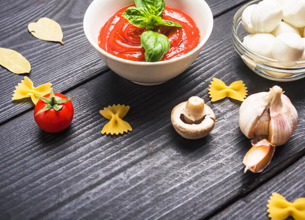 Bowl of tomato sauce with basil and ingredients