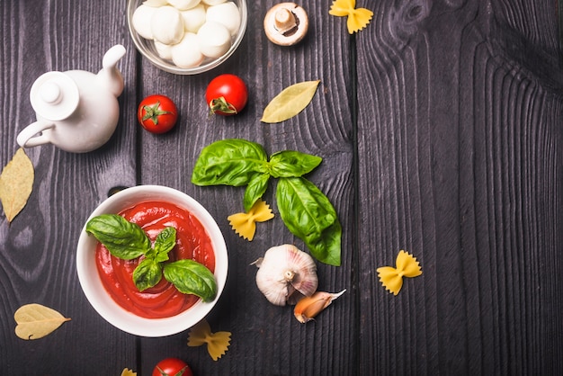 Bowl of tomato sauce with ingredients on table