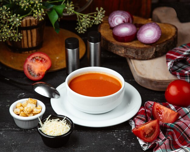 bowl of tomato soup served with bread stuffing and grated cheese