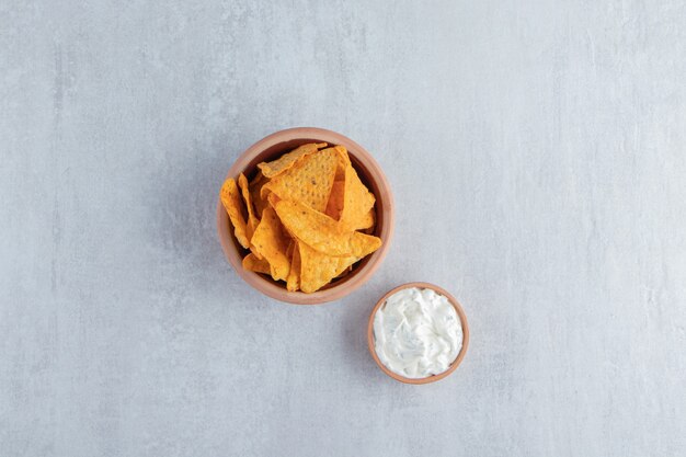 Bowl of tortilla chips and special sauce on stone.