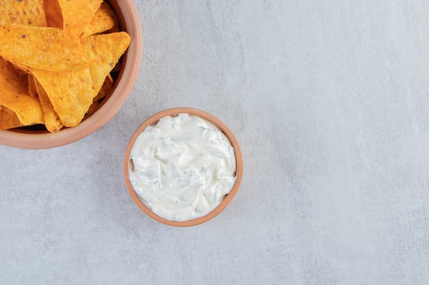 Bowl of tortilla chips and special sauce on stone.