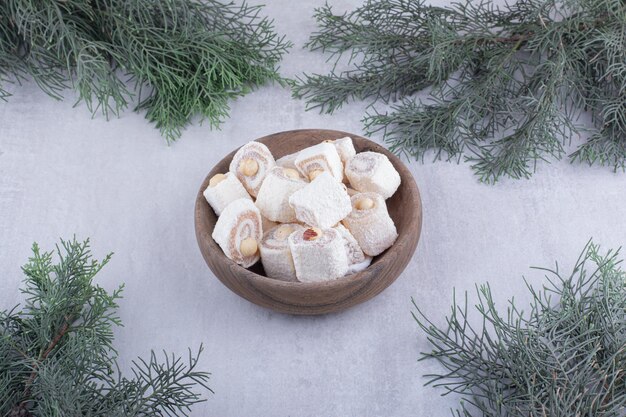 Free photo bowl of turkish delight and pine branches on white surface