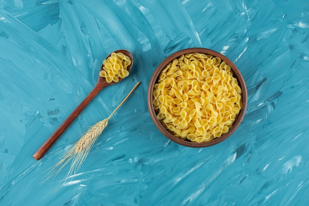 Bowl of uncooked dry macaroni placed on marble surface