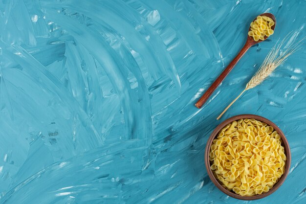 Bowl of uncooked dry macaroni placed on marble surface