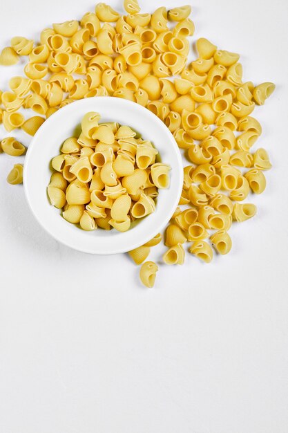 A bowl of uncooked pasta on white background