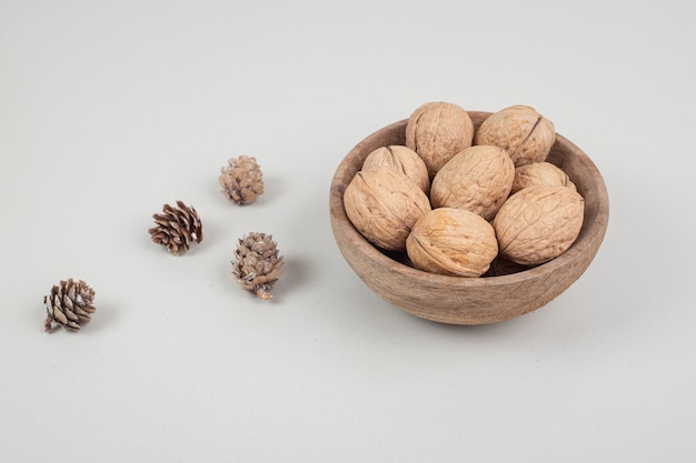 Bowl of walnuts and pinecones on beige surface