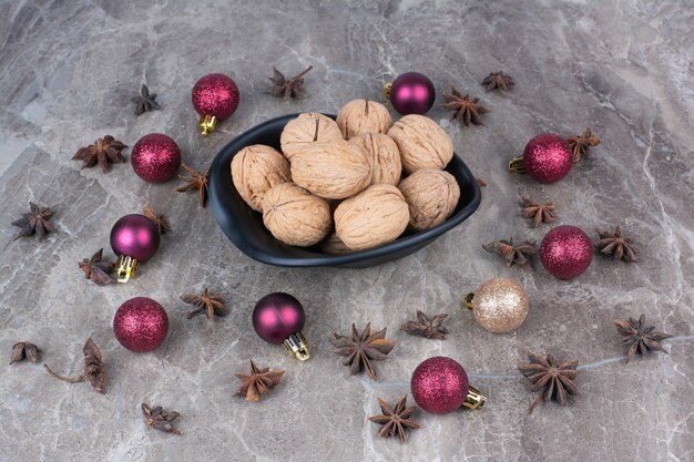Bowl of walnuts with cloves and Christmas balls. 