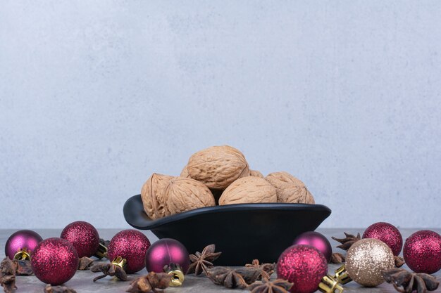 Bowl of walnuts with cloves and Christmas balls. 