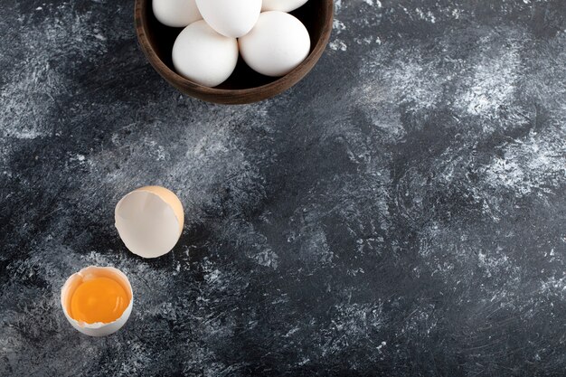 Bowl of white eggs and yolk on marble surface. 