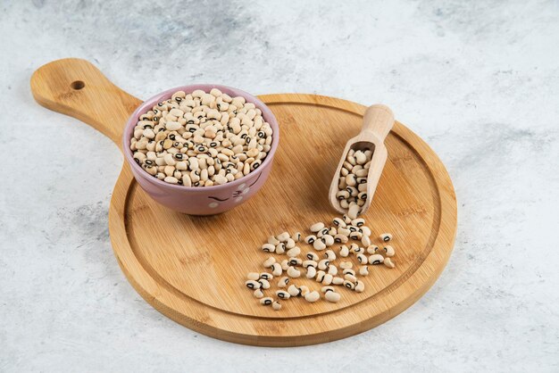 Bowl of white kidney beans with spoon on cutting board.