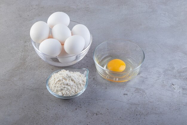 흰색 원시 계란과 돌 테이블에 밀가루의 그릇.