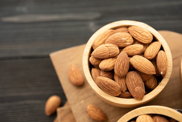 Bowl with almond on a wooden table.