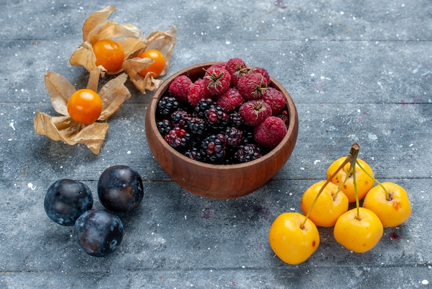 Foto gratuita ciotola con frutti di bosco freschi e frutti maturi sulla scrivania grigia, frutti di bosco freschi mellow forest