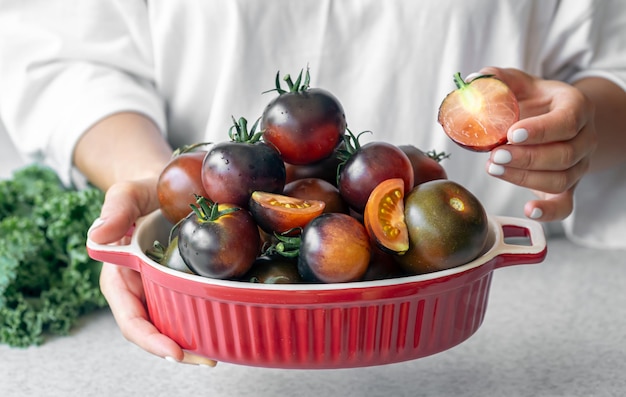 Free photo bowl with black tomatoes in female hands