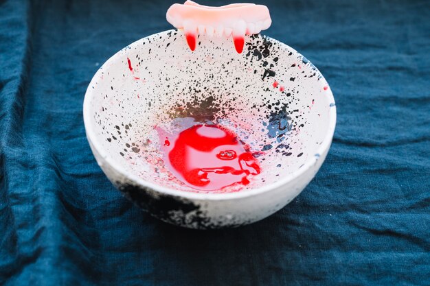 Bowl with blood and vampire teeth 