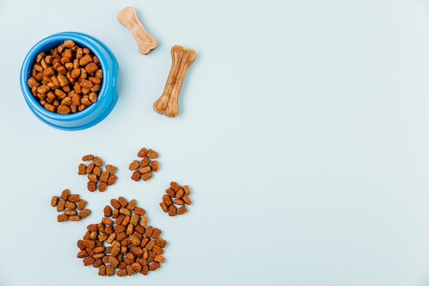 Bowl with feed and paw figure on light background