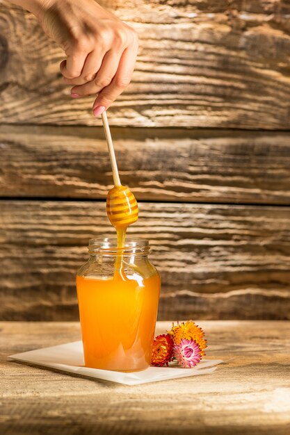 The bowl with honey on wooden table.The bank of honey stay near wooden spoon