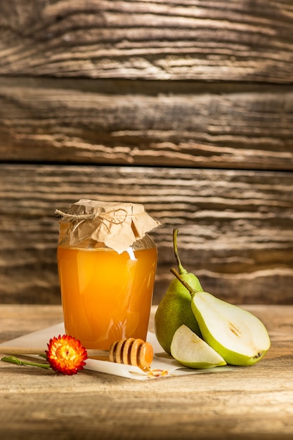 The bowl with honey on wooden table.The bank of honey stay near wooden spoon