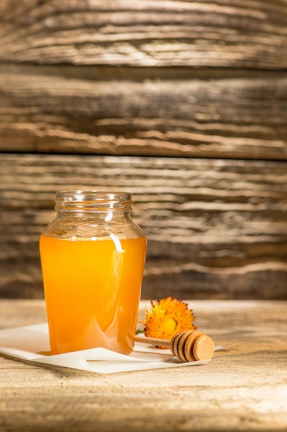 Free photo the bowl with honey on wooden table.the bank of honey stay near wooden spoon