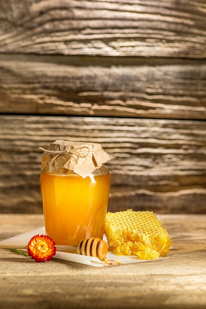 Чаша с медом на деревянном столе. Банк меда рядом с деревянной ложкой