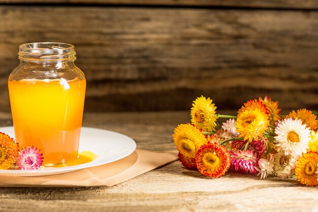 The bowl with honey on wooden table.The bank of honey stay near wooden spoon