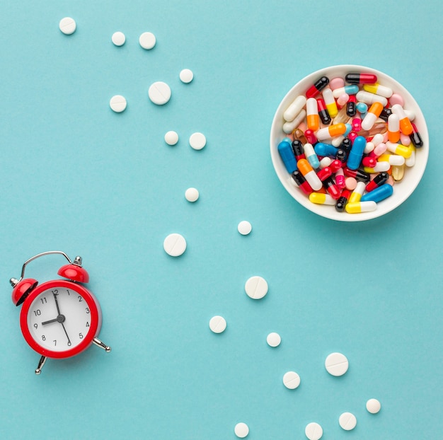 Free photo bowl with pills and clock beside