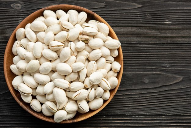 Bowl with pistachios on a wooden table.