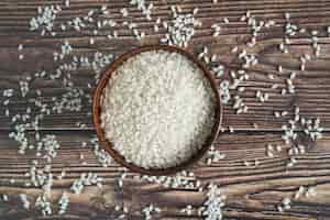 Free photo bowl with rice on desk with scattered grains